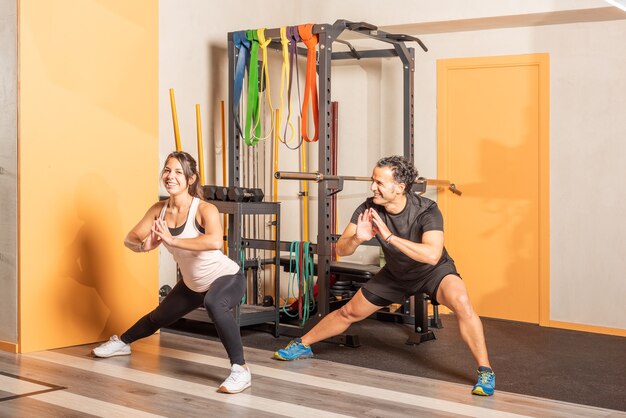 Gente alegre haciendo ejercicio de estiramiento de aductores en el gimnasio, mujer mirando a cámara. Concepto de ejercicio en el gimnasio.