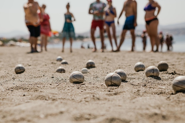 gente amable jugando petanca en la playa cerca de un hotel lleno de veraneantes