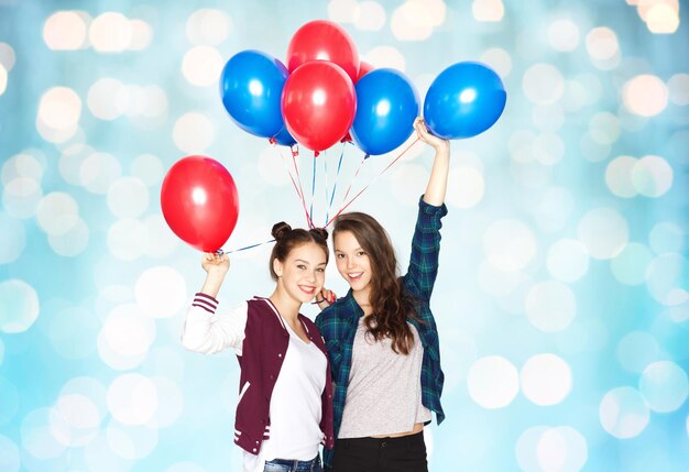 Foto gente, amigos, adolescentes, vacaciones y concepto de fiesta - felices y sonrientes adolescentes bonitas con globos de helio sobre fondo azul de luces navideñas