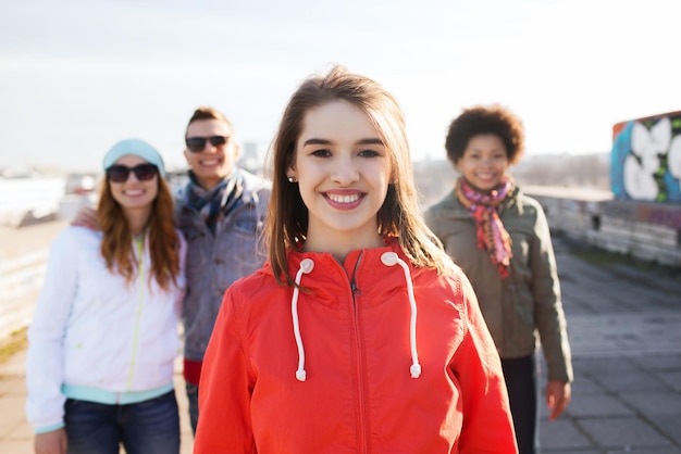 gente, amistad y concepto internacional - mujer joven feliz o adolescente frente a sus amigos en la calle de la ciudad