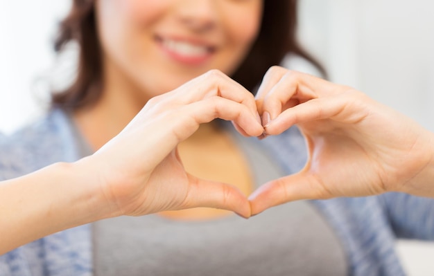 gente, amor, día de san valentín, caridad y concepto de gesto - cerca de una joven feliz mostrando el corazón con las manos