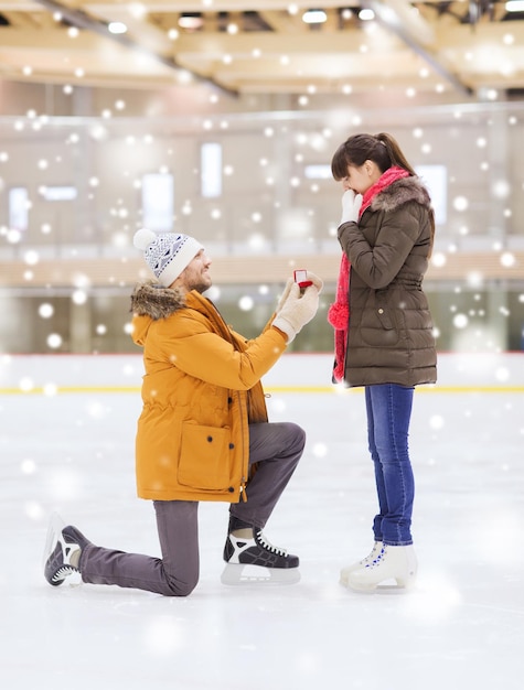 gente, amor, propuesta, concepto de deporte y ocio - pareja feliz con anillo de compromiso en la pista de patinaje