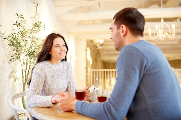 gente, amor, romance y concepto de citas - pareja feliz bebiendo té y tomándose de la mano en un café o restaurante