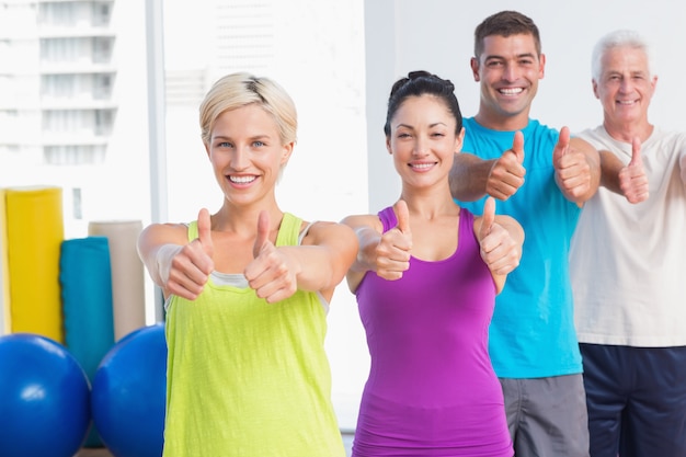 Gente apta gesticular pulgares arriba en el gimnasio