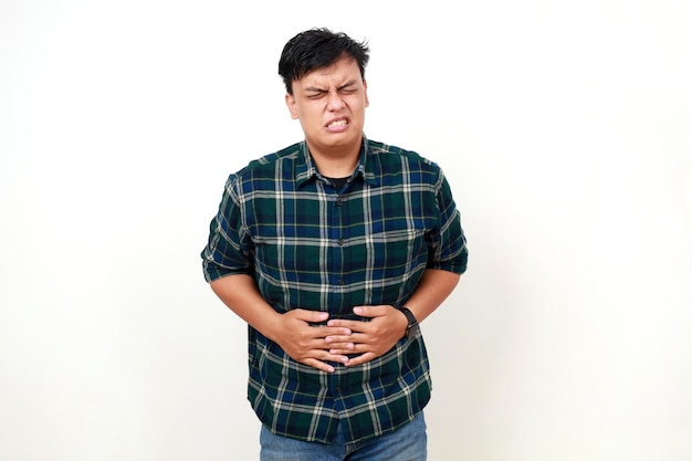 Gente atención médica y problema de salud concepto infeliz joven asiático que sufre de dolor de estómago sobre fondo blanco