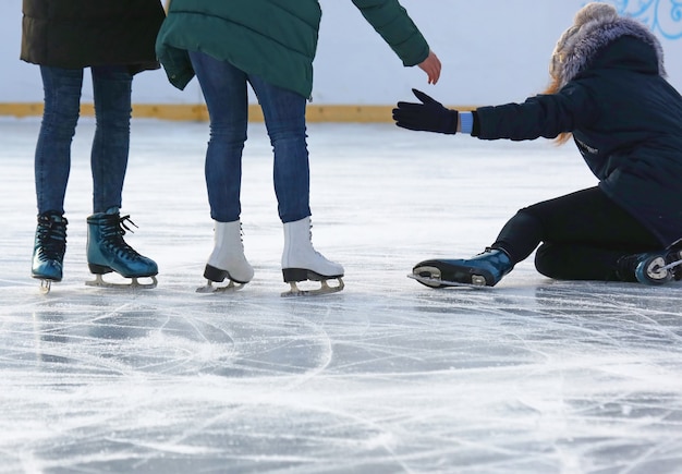 Foto la gente ayuda a levantarse después de una caída patinando en la pista de hielo.