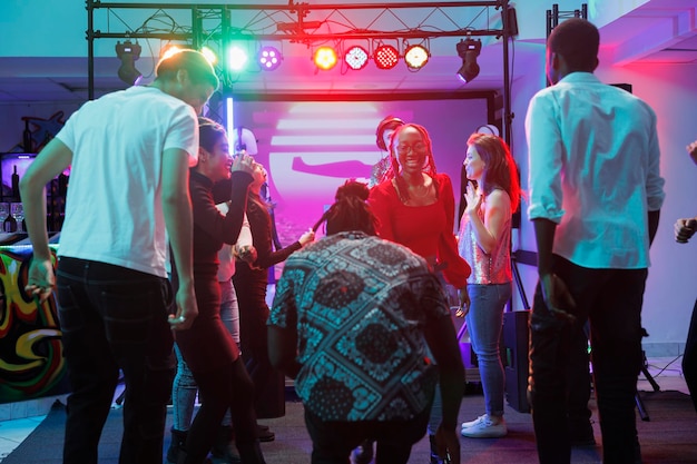 Gente bailando en una discoteca llena de jóvenes clubbers diversos divirtiéndose y disfrutando de la música en vivo. Amigos felices moviéndose al ritmo de la pista de baile mientras asisten a una fiesta disco en el club