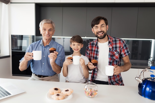 La gente bebe té en la cocina y posa con magdalenas.