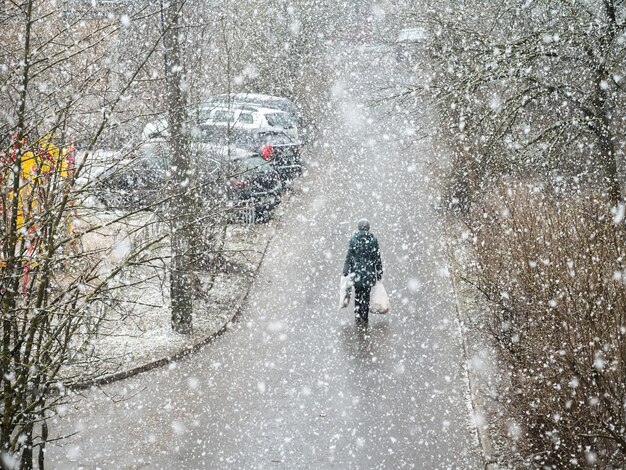 La gente con bolsas en las manos bajo una fuerte nevada está caminando