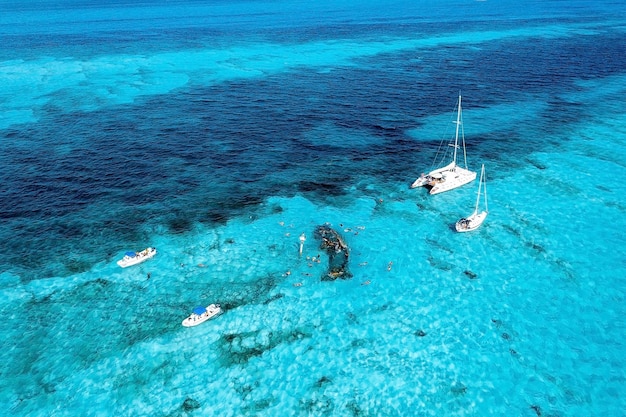 Gente buceando alrededor del naufragio cerca de las Bahamas en el mar Caribe. Hermosa agua turquesa con gente nadando con peces, vista aérea.