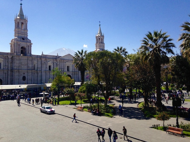 Gente en la calle en medio de árboles y edificios contra el cielo