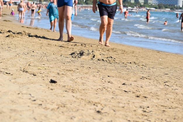 La gente camina a la orilla del mar sobre la arena. los turistas en el mar caminan por la costa. temporada de vacaciones turísticas en los trópicos