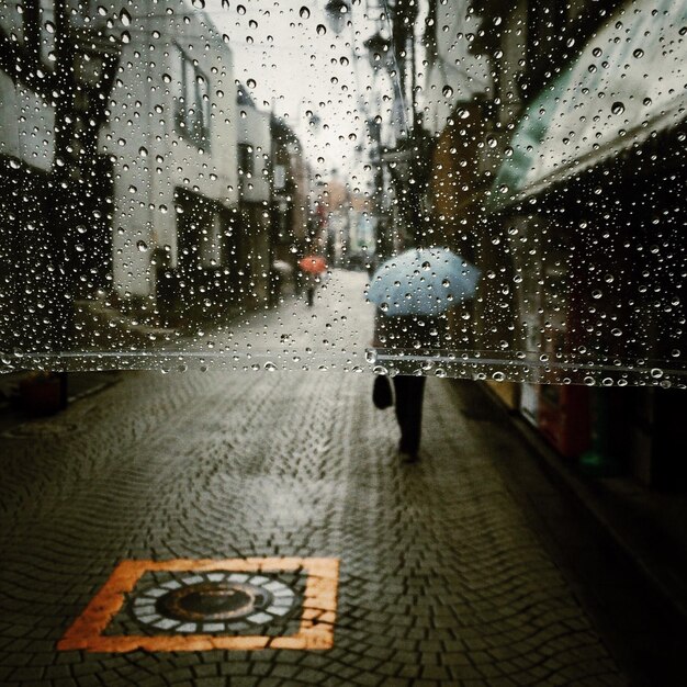 Foto gente caminando por la calle a través de vidrio mojado durante la temporada de lluvias