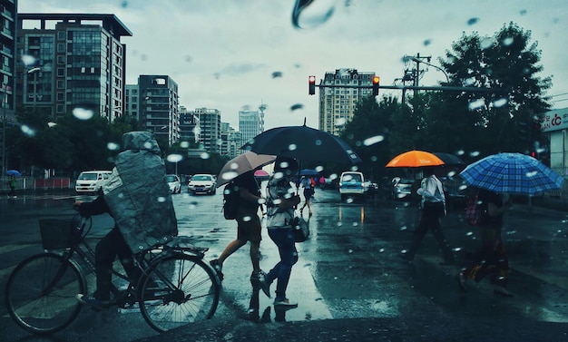Gente caminando por el cruce de cebras durante la temporada de lluvias a través de una ventana de vidrio