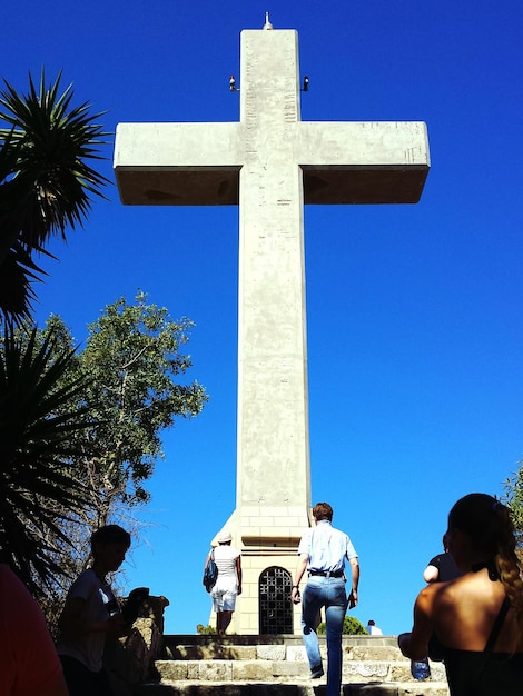 Foto la gente caminando frente a la estatua de la cruz