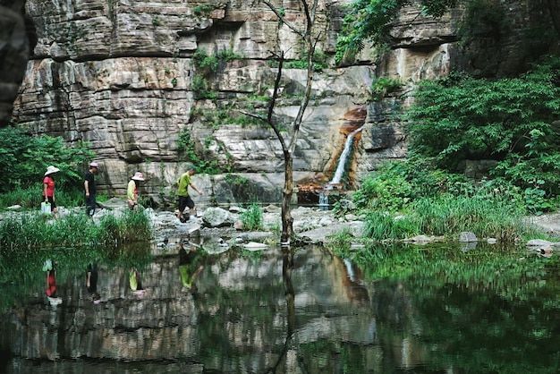 Gente caminando por el lago contra montañas rocosas