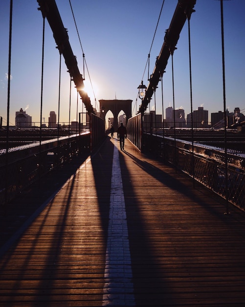 Gente caminando por el puente contra el cielo durante la puesta de sol