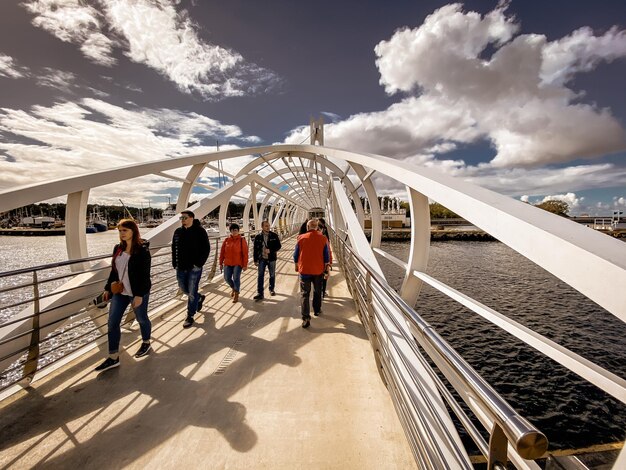 Foto gente caminando por el puente ferroviario contra el cielo