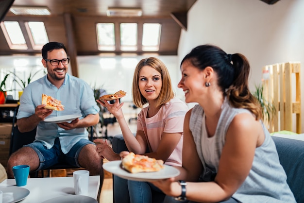 Gente caucásica hermosa que come pizza dentro.