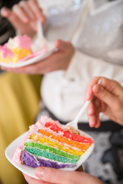 Foto gente comiendo pastel de arco iris delicioso colorido casero