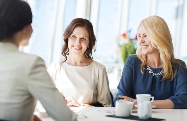 gente, comunicación y concepto de estilo de vida - mujeres felices tomando café y hablando en el restaurante