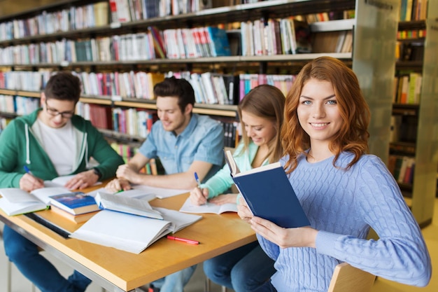 gente, conocimiento, educación, literatura y concepto escolar - estudiantes felices leyendo libros y preparándose para los exámenes en la biblioteca