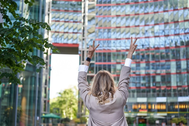 Gente corporativa vista trasera de la mujer de negocios levantando las manos en celebración triunfante lograr el objetivo