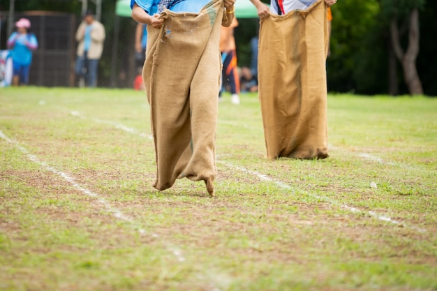 Gente corriendo carrera de sacos en campo en cultura de campo