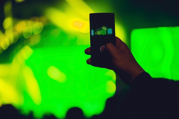 Gente disfrutando de conciertos de rock y tomando fotos con el teléfono celular en el festival de música.