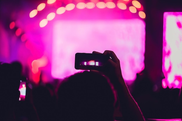 Gente disfrutando de conciertos de rock y tomando fotos con el teléfono celular en el festival de música