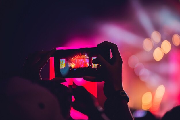 Gente disfrutando de conciertos de rock y tomando fotos con el teléfono celular en el festival de música