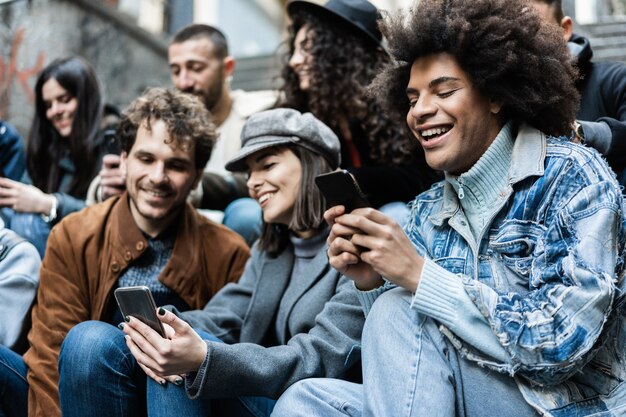 Gente diversa feliz usando teléfonos móviles al aire libre en la ciudad - Centrarse en la cara del chico africano