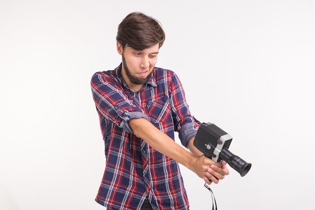 Gente divertida, foto y concepto vintage - joven con cámara vintage sobre superficie blanca