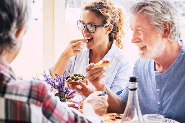 Gente divirtiéndose y almorzando en la mesa del comedor. Pasar tiempo de calidad con familiares y amigos. Amante de la feliz familia de varias generaciones disfrutando juntos de comida y bebida