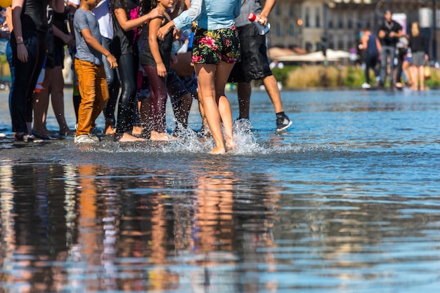 Gente divirtiéndose en una fuente de espejo en frente de la Place de la Bourse en Burdeos, Francia