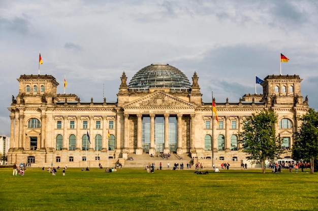 La gente en el edificio del Reichstag contra el cielo nublado