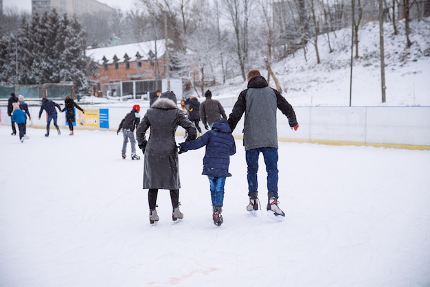 La gente esquía en la pista de hielo exterior en el día de invierno