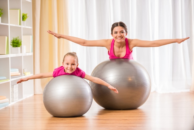 La gente está haciendo ejercicios físicos en la pelota de fitness en casa.