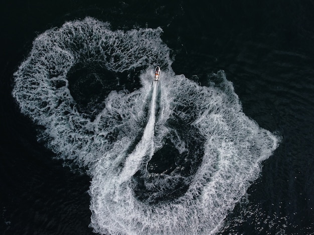 La gente está jugando una moto de agua en el mar dejando huellas blancas abstractas en la parte superior de la antena de agua