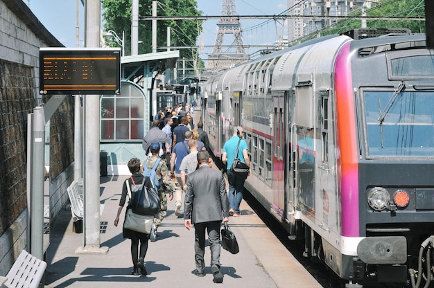 Gente en la estación con el tren contra la Torre Eiffel