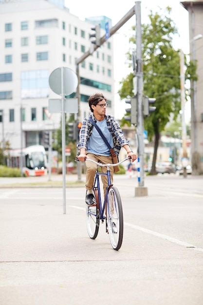 gente, estilo, ocio y estilo de vida - joven hipster con bandolera montando bicicleta fija en la calle de la ciudad