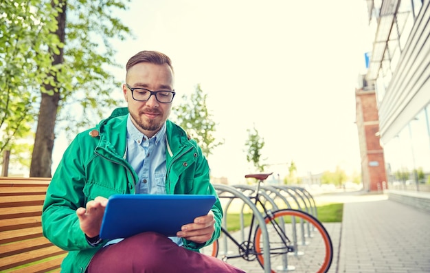 gente, estilo, tecnología y estilo de vida - feliz joven hipster con tablet pc y bicicleta fixie sentado en un banco en la ciudad