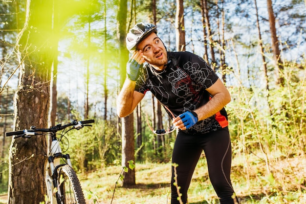 Gente con un estilo de vida activo y saludable y una toma trasera extrema de un ciclista profesional caucásico con ropa de ciclismo con casco recreativo después de un duro entrenamiento con bicicleta en el bosque o las montañas