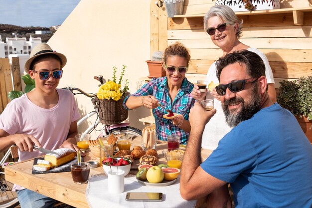 Foto gente en familia disfrutando del desayuno en el balcón