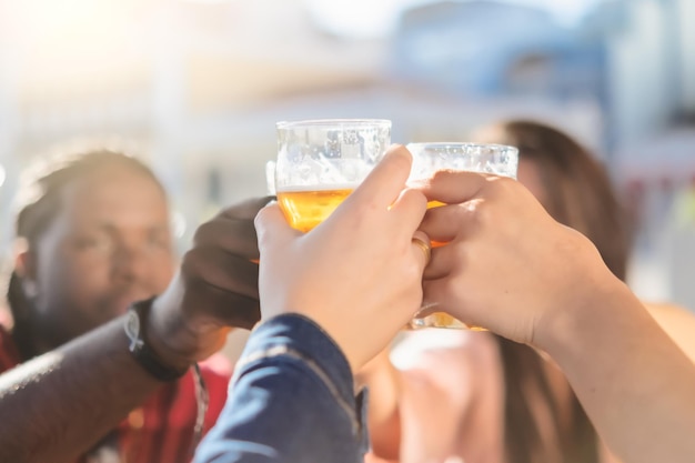 Gente feliz brindando con cerveza en el bar de la cervecería al aire libre Jóvenes amigos divirtiéndose juntos