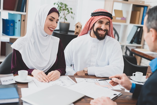 La gente feliz firma contrato pareja árabe en agente de bienes raíces.