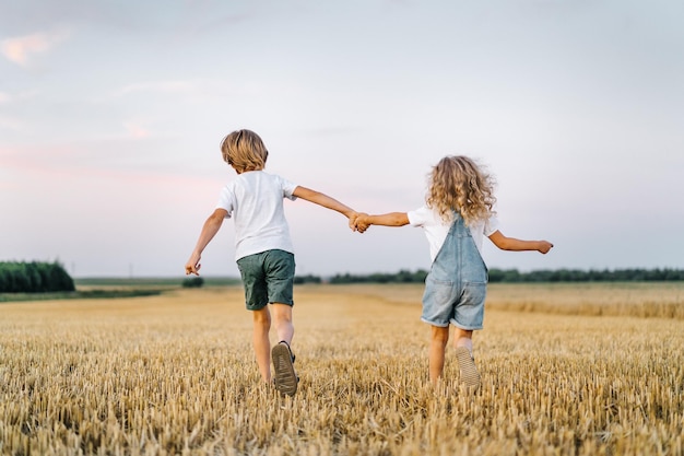 Gente feliz y libre, niños corriendo por el trigal biselado, gente de espaldas.