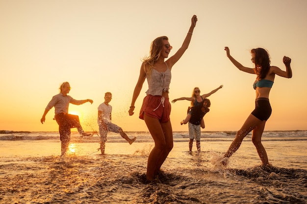 Gente feliz multinacional multicultural corriendo hacia el sol sin preocupaciones y felices vacaciones en el mar