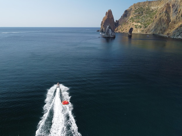 La gente feliz va a nadar en un colchón de aire detrás de una moto de agua, los turistas montan el inflable