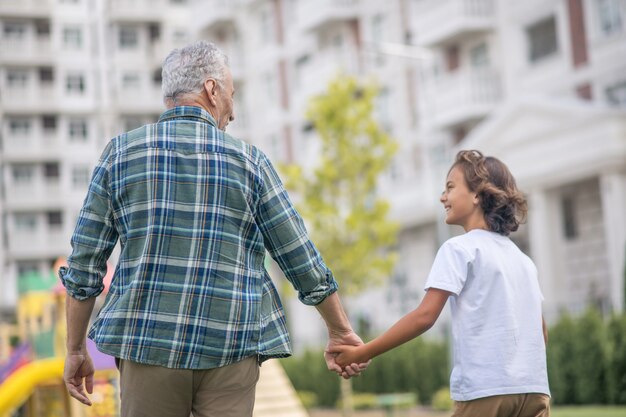 Gente feliz. Papá e hijo caminando juntos de la mano y luciendo felices